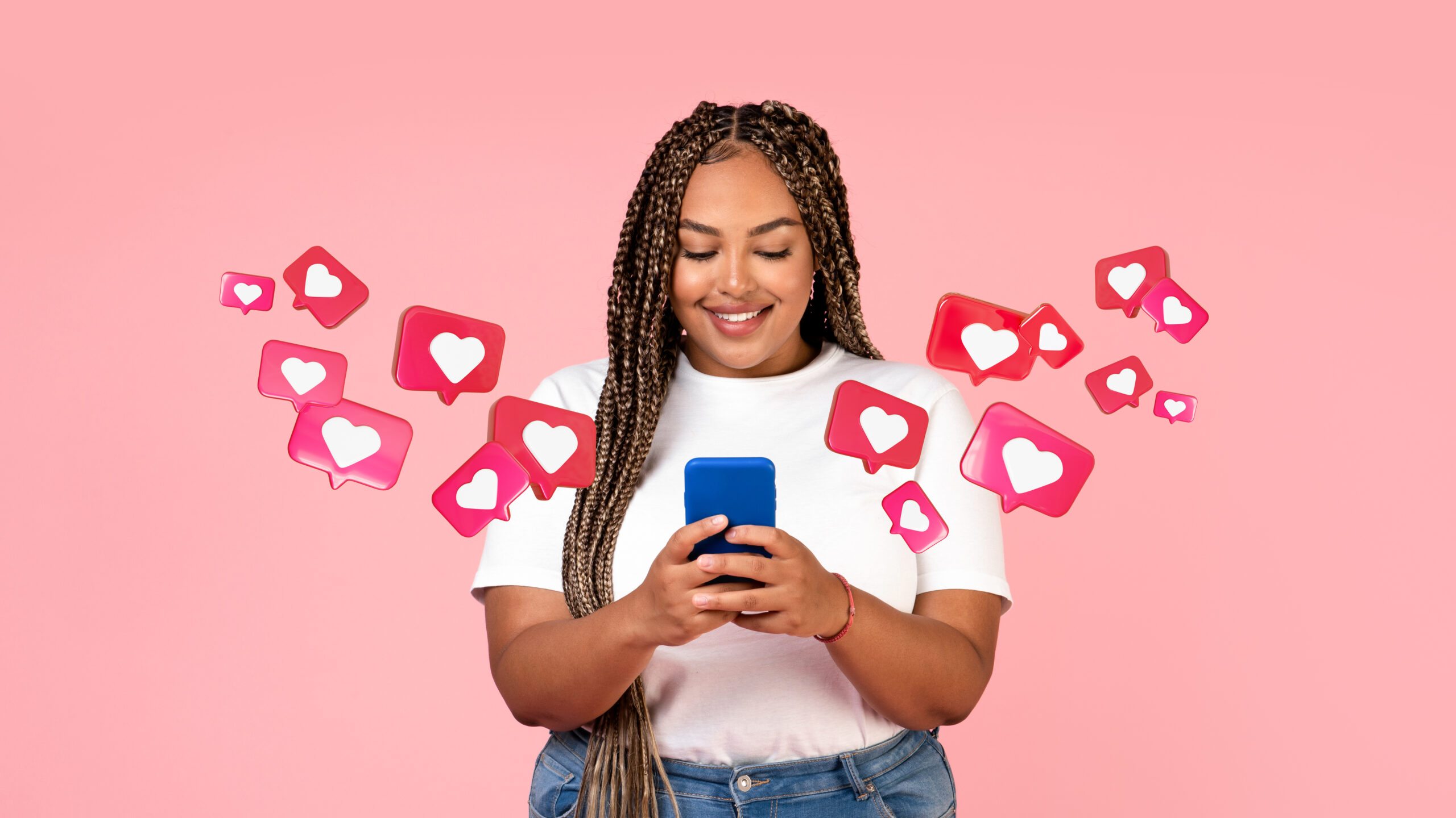 Cheerful young african american female with pigtails has romantic chat with hearts on smartphone